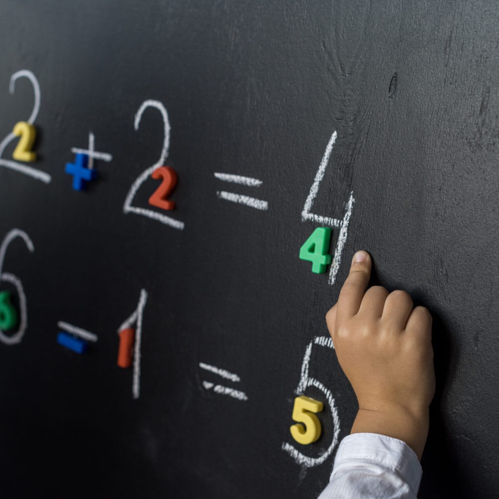 cropped shot of child studying numbers on chalkboard